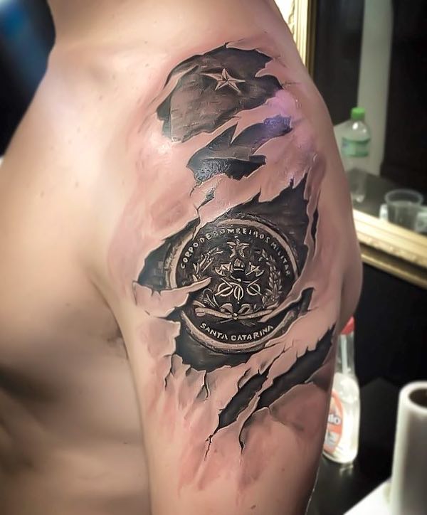 Torn effect badge tattoo on the sleeve by @luansza